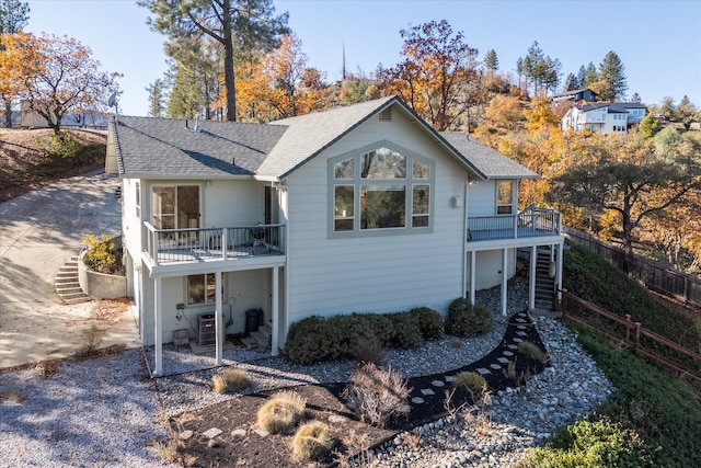 rear view of property featuring a balcony and central AC