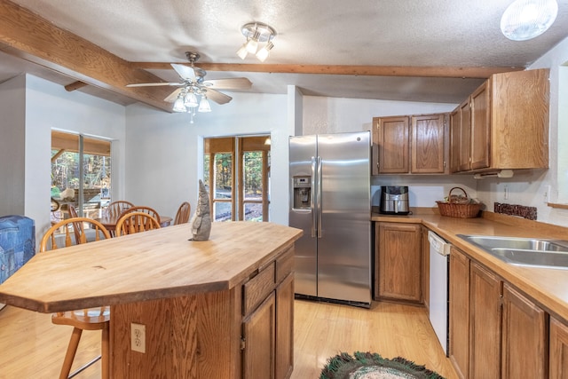 kitchen with stainless steel fridge, a kitchen breakfast bar, a textured ceiling, light hardwood / wood-style flooring, and dishwasher