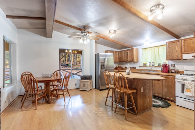 kitchen with a healthy amount of sunlight, light wood-type flooring, stainless steel fridge with ice dispenser, and white range with gas stovetop