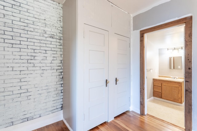 interior space with brick wall, light wood-type flooring, and sink