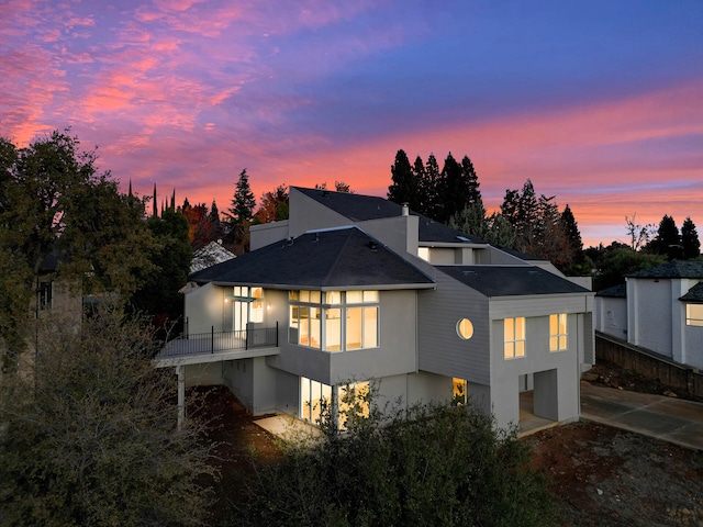 back house at dusk with a balcony