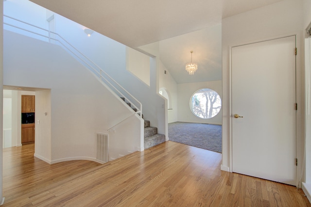 foyer with high vaulted ceiling, light hardwood / wood-style floors, and an inviting chandelier