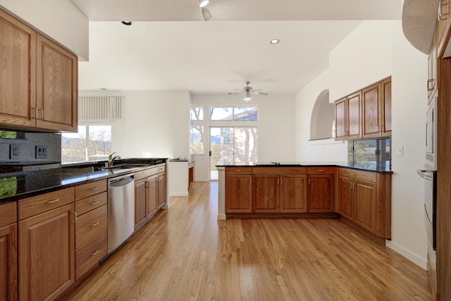 kitchen featuring backsplash, ceiling fan, light wood-type flooring, kitchen peninsula, and stainless steel appliances