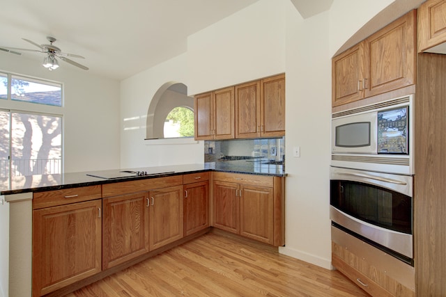 kitchen with ceiling fan, backsplash, dark stone countertops, light hardwood / wood-style floors, and appliances with stainless steel finishes