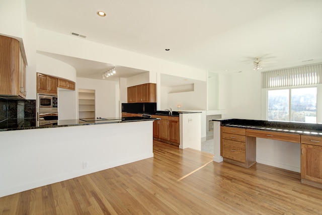 kitchen featuring ceiling fan, sink, stainless steel appliances, light hardwood / wood-style flooring, and backsplash