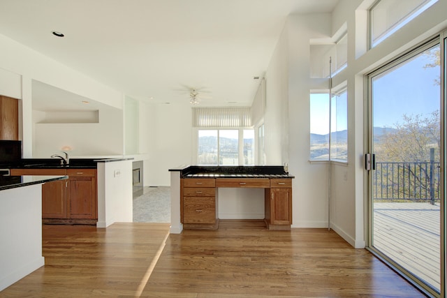 kitchen with kitchen peninsula, ceiling fan, sink, a mountain view, and hardwood / wood-style floors