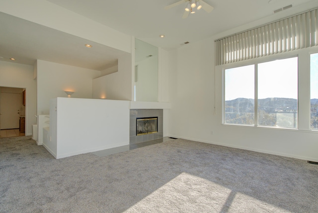 unfurnished living room with a mountain view, light carpet, a fireplace, and ceiling fan