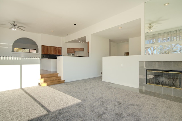 unfurnished living room with light carpet, a tile fireplace, and plenty of natural light