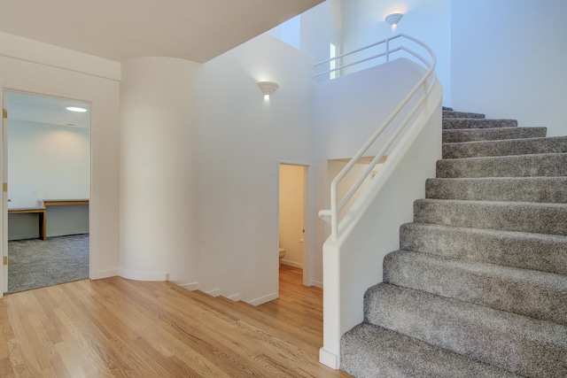 staircase featuring a high ceiling and hardwood / wood-style flooring