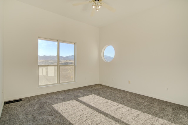 carpeted empty room featuring a mountain view and ceiling fan