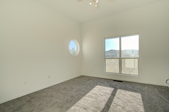 carpeted empty room with a mountain view and ceiling fan