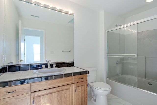 full bathroom featuring combined bath / shower with glass door, vanity, and toilet