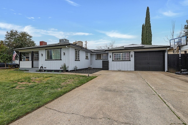 single story home with a porch, a garage, a front yard, and solar panels