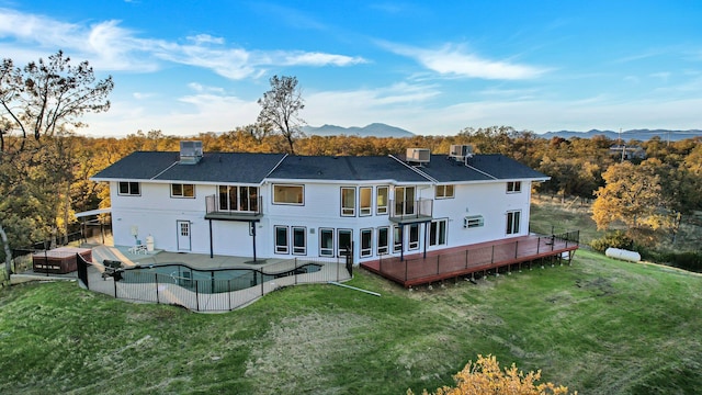 back of house featuring a mountain view, a balcony, and a lawn