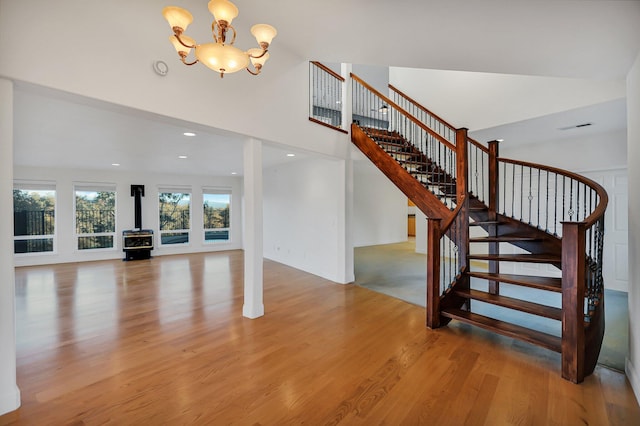 stairway with a wood stove, hardwood / wood-style floors, and a chandelier