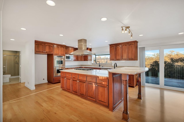 kitchen featuring island exhaust hood, a kitchen breakfast bar, stainless steel appliances, light hardwood / wood-style flooring, and a kitchen island