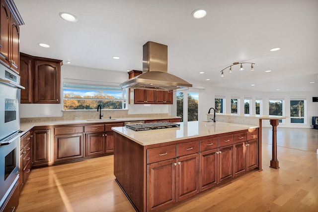 kitchen featuring appliances with stainless steel finishes, a center island, island range hood, and light hardwood / wood-style floors