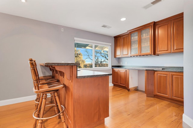 kitchen with a kitchen bar, kitchen peninsula, and light hardwood / wood-style flooring