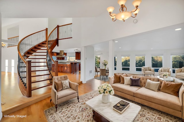 living room with light hardwood / wood-style floors, a high ceiling, and an inviting chandelier