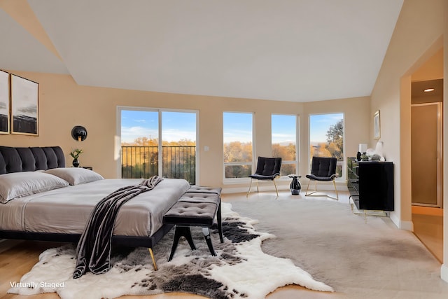 bedroom with access to exterior, light hardwood / wood-style flooring, and vaulted ceiling