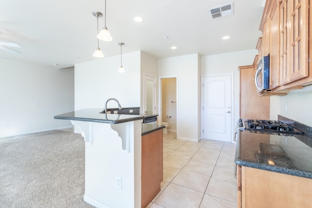 kitchen with light carpet, a center island with sink, hanging light fixtures, ceiling fan, and gas stovetop