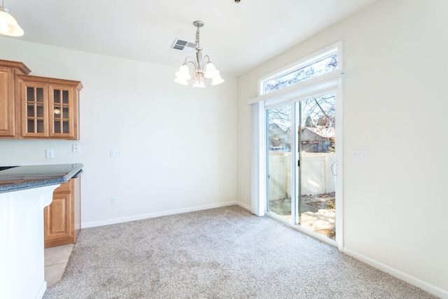 unfurnished dining area with a notable chandelier and light colored carpet