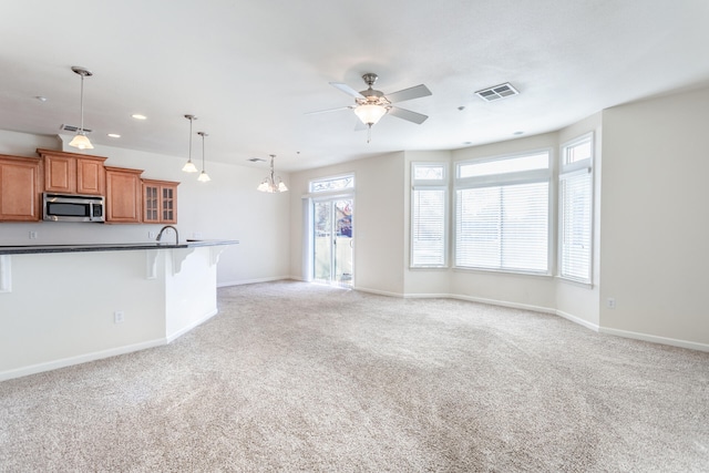 unfurnished living room with ceiling fan with notable chandelier and light carpet