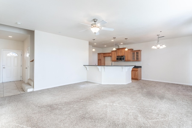 kitchen featuring a kitchen breakfast bar, ceiling fan with notable chandelier, decorative light fixtures, light colored carpet, and kitchen peninsula