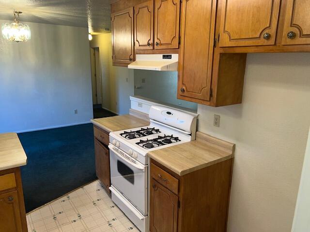 kitchen featuring pendant lighting, white gas stove, and a notable chandelier