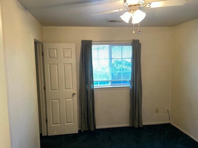 empty room with dark carpet and ceiling fan