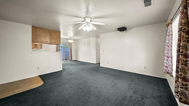 spare room featuring visible vents, baseboards, dark colored carpet, a textured ceiling, and a ceiling fan