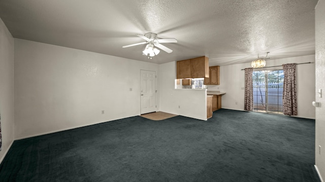 unfurnished living room with dark carpet, a textured ceiling, ceiling fan with notable chandelier, and baseboards