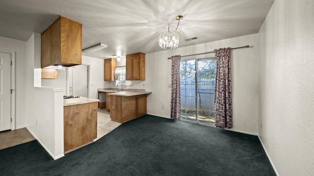 kitchen featuring brown cabinets, a sink, light countertops, baseboards, and visible vents