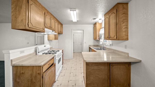 kitchen with a sink, light countertops, a peninsula, white range with gas stovetop, and light floors