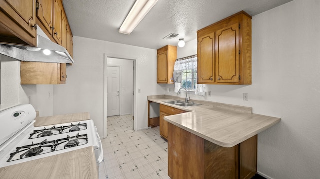 kitchen featuring visible vents, a peninsula, light floors, white gas stove, and a sink