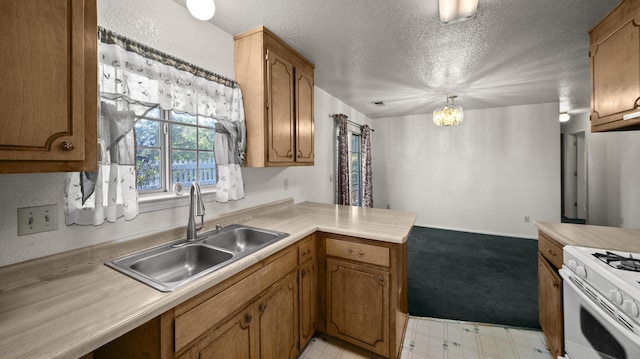 kitchen with a sink, a textured ceiling, a chandelier, a peninsula, and white gas stove