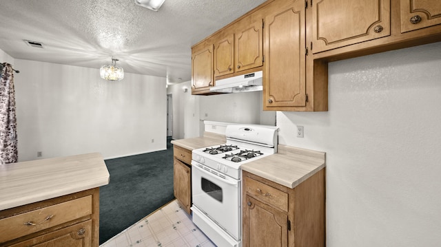kitchen featuring a textured ceiling, light countertops, white gas range oven, light floors, and under cabinet range hood
