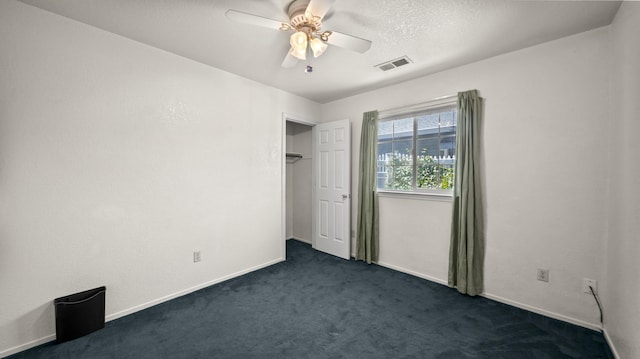 empty room featuring baseboards, ceiling fan, dark carpet, and visible vents
