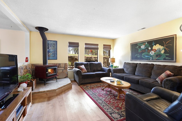 living room with hardwood / wood-style floors, a textured ceiling, and a wood stove