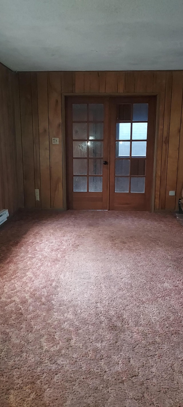 unfurnished room featuring carpet flooring, a textured ceiling, and wooden walls