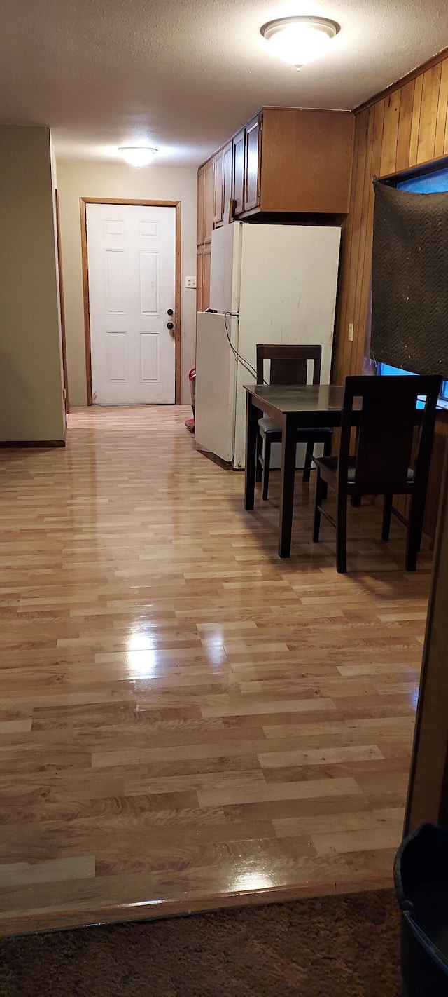 dining room with wood walls, light hardwood / wood-style floors, and a textured ceiling