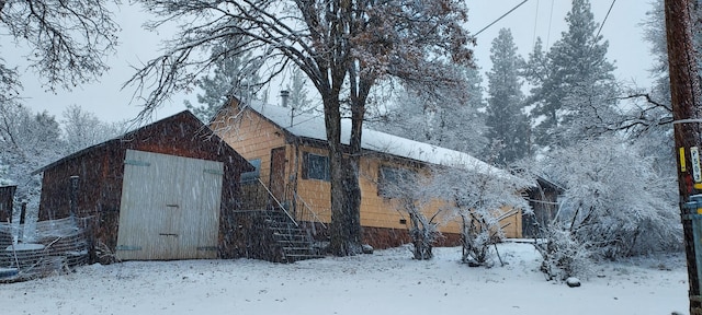 snow covered property featuring an outdoor structure