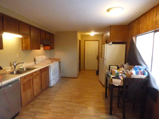 kitchen featuring white appliances, sink, wooden walls, light wood-type flooring, and extractor fan