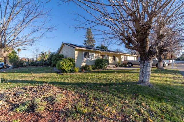 ranch-style home with a front yard and solar panels