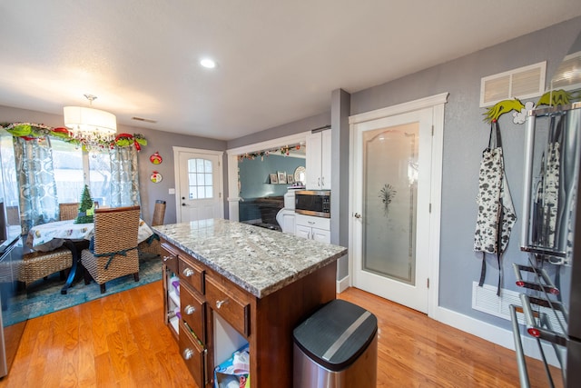 kitchen featuring white cabinets, light stone counters, and light wood-type flooring