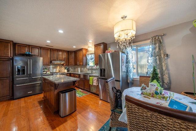 kitchen with a center island, a healthy amount of sunlight, light wood-type flooring, and appliances with stainless steel finishes