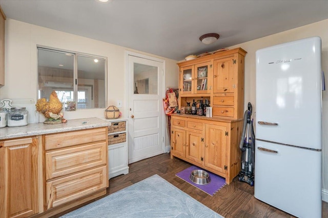 kitchen featuring white fridge, light stone counters, and dark wood-type flooring