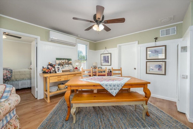 dining area featuring a wall unit AC, ceiling fan, crown molding, and light wood-type flooring