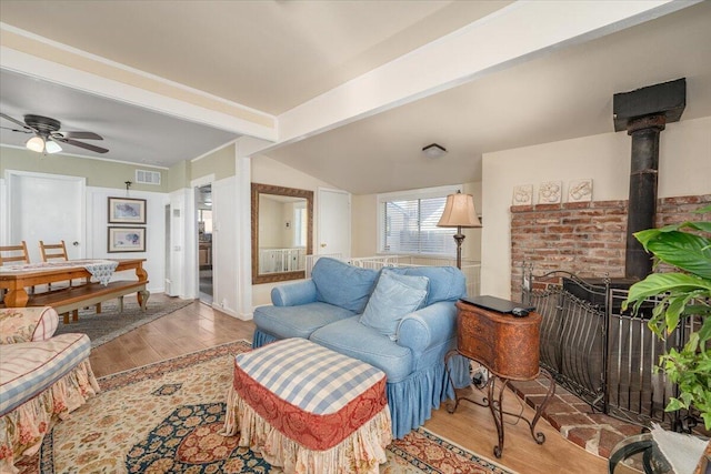 living room featuring hardwood / wood-style flooring, ceiling fan, lofted ceiling with beams, and a wood stove