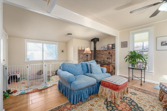 living room featuring beam ceiling, a wood stove, plenty of natural light, and hardwood / wood-style flooring